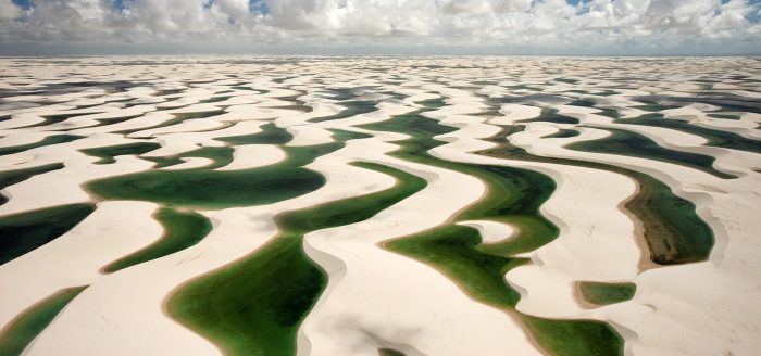 19 Jul 2009, Brazil --- Lençois Maranhenses National Park is a coastal dune field (measuring some 155,000 hectares) that is flooded with fresh water lakes during the January to May rainy season.  Strong prevailing winds from the East mobilize the barchan dunes during the dry season and, combined with the equatorial sun, evaporate the lakes and prevent permanent vegetation from taking root.  The dunes are composed of quartz grains that are eroded from the granite and washed down from the Parnaiba River and then carrie --- Image by © George Steinmetz/Corbis